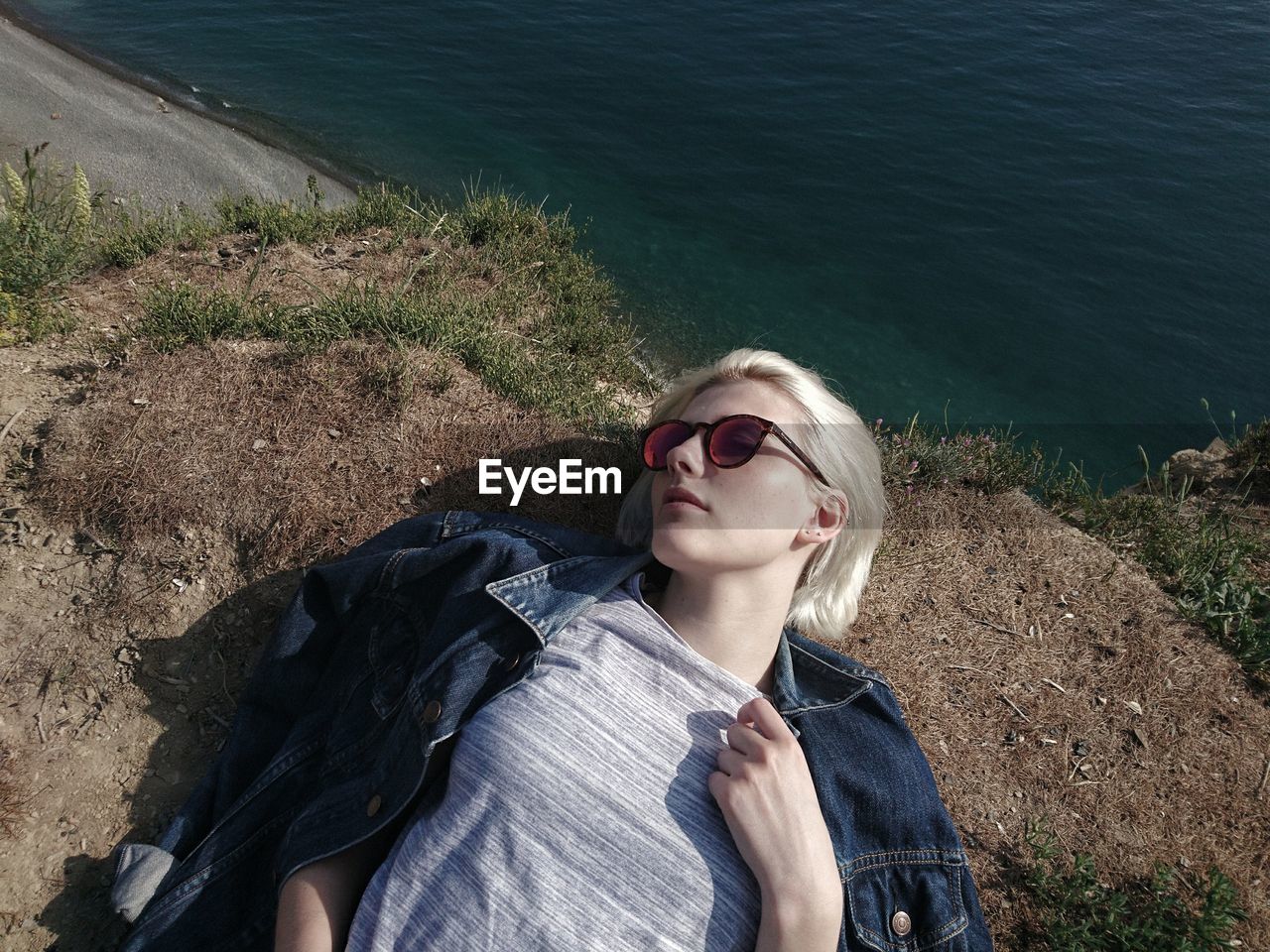 High angle view of woman lying on rock formation by sea