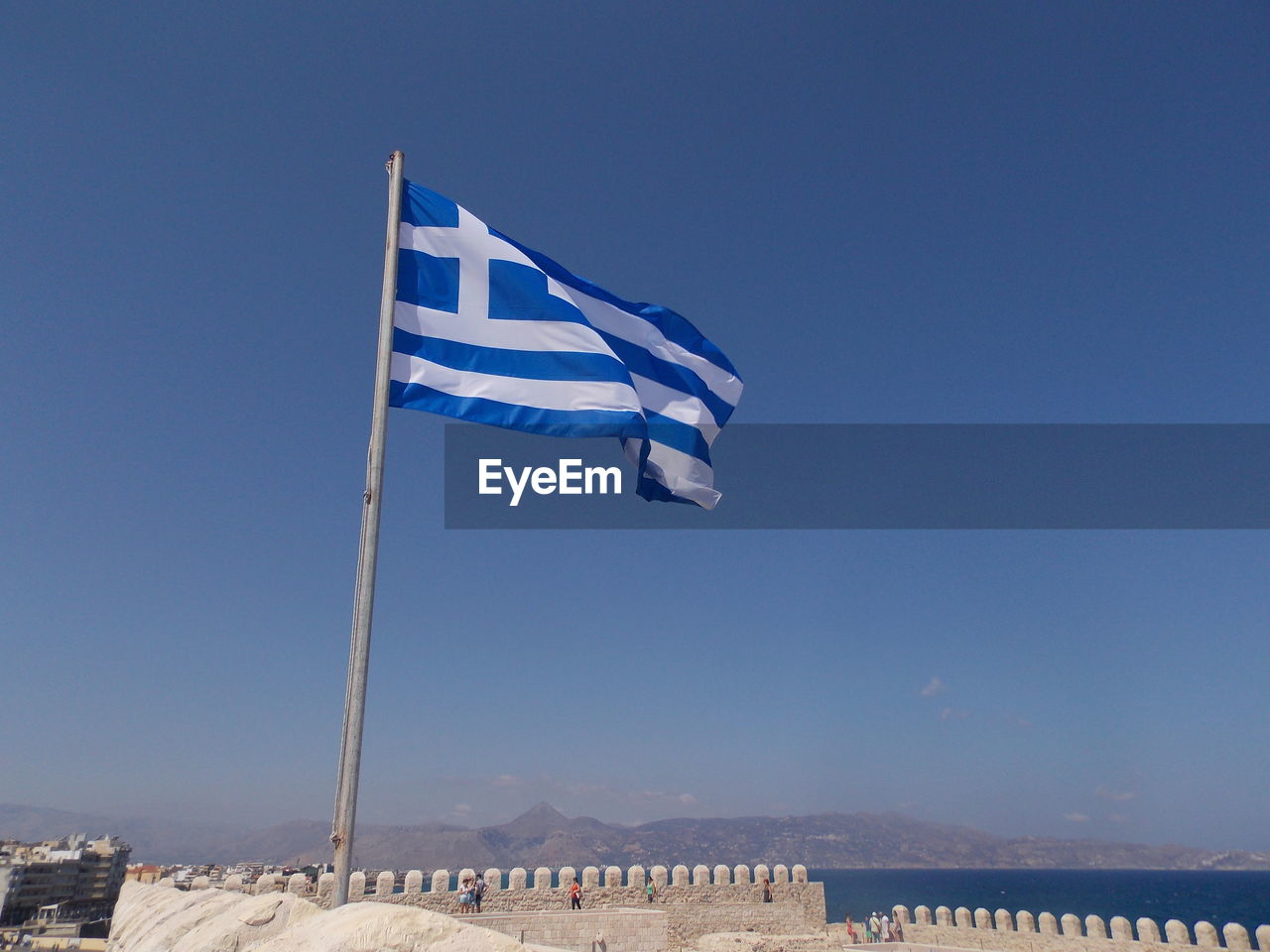 Low angle view of greek flag against clear blue sky