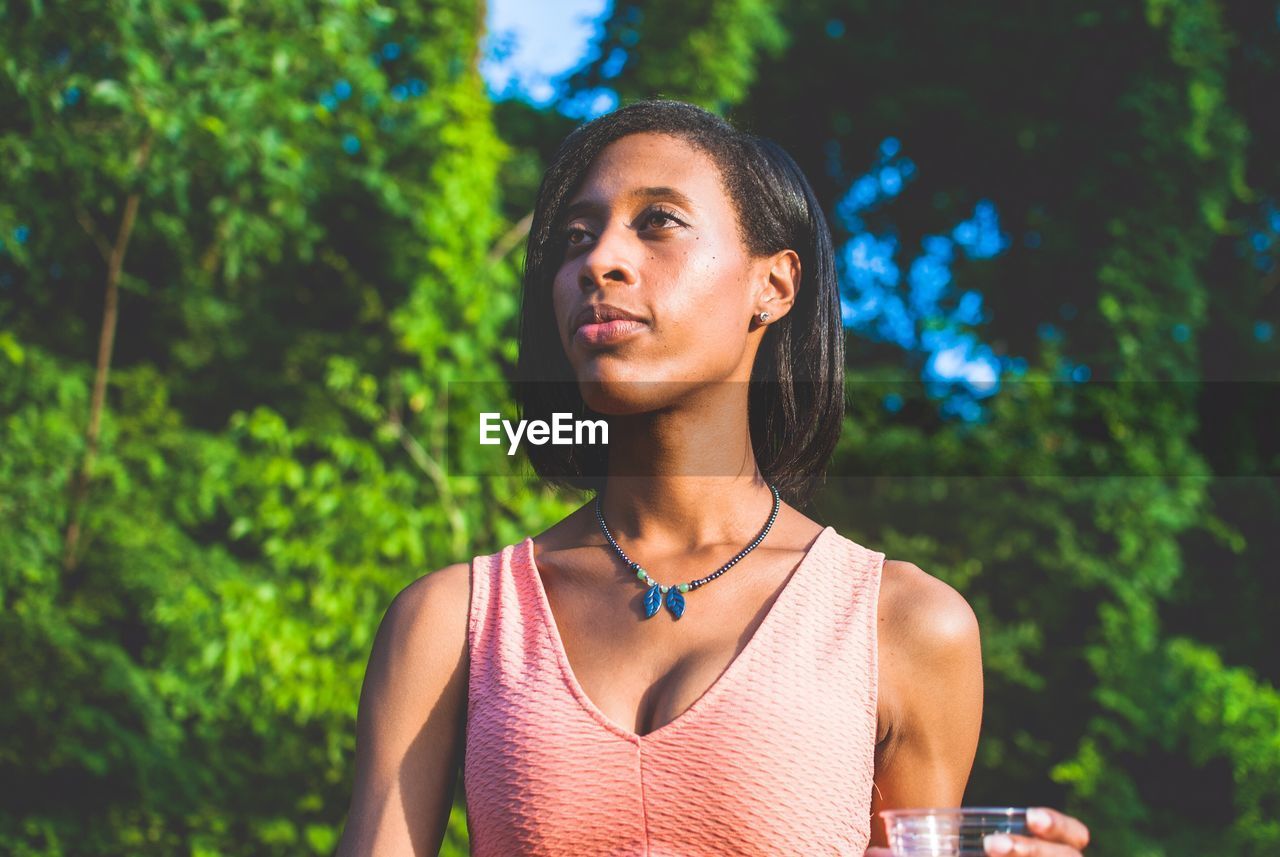 CLOSE-UP OF BEAUTIFUL WOMAN AGAINST TREES