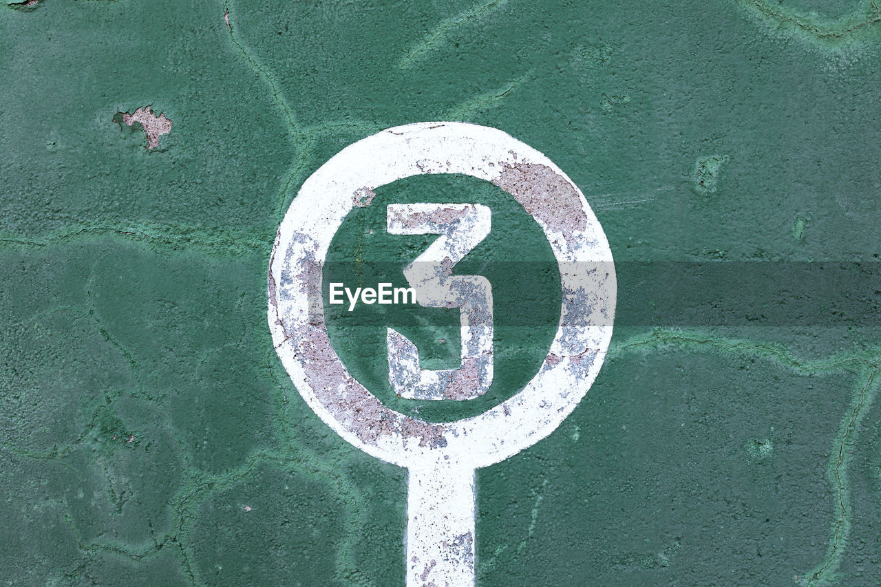 Weathered green wall with peeling paint and number three showing concept of winner