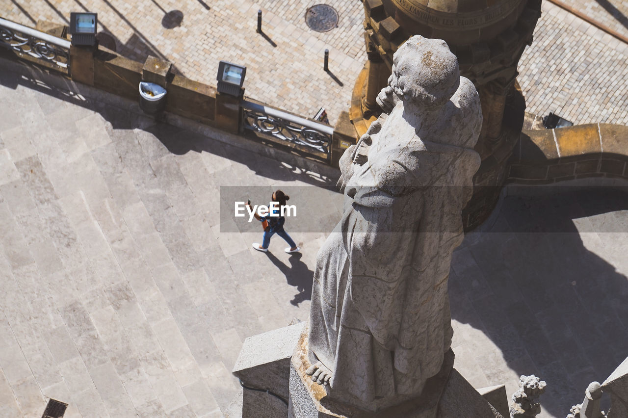 High angle view of woman walking on footpath by statue