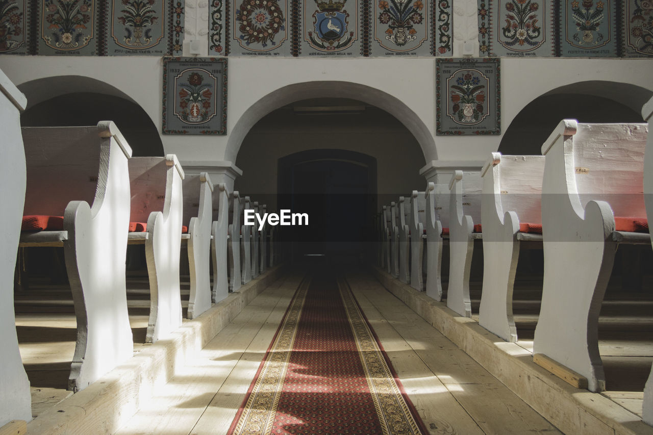 Carpet on walkway amidst pews in church