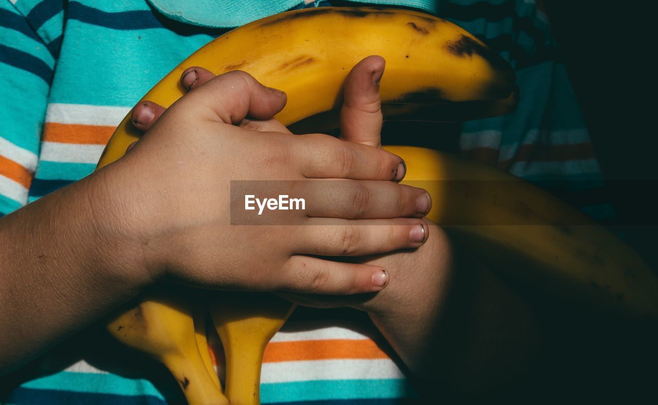 Midsection of child holding bananas