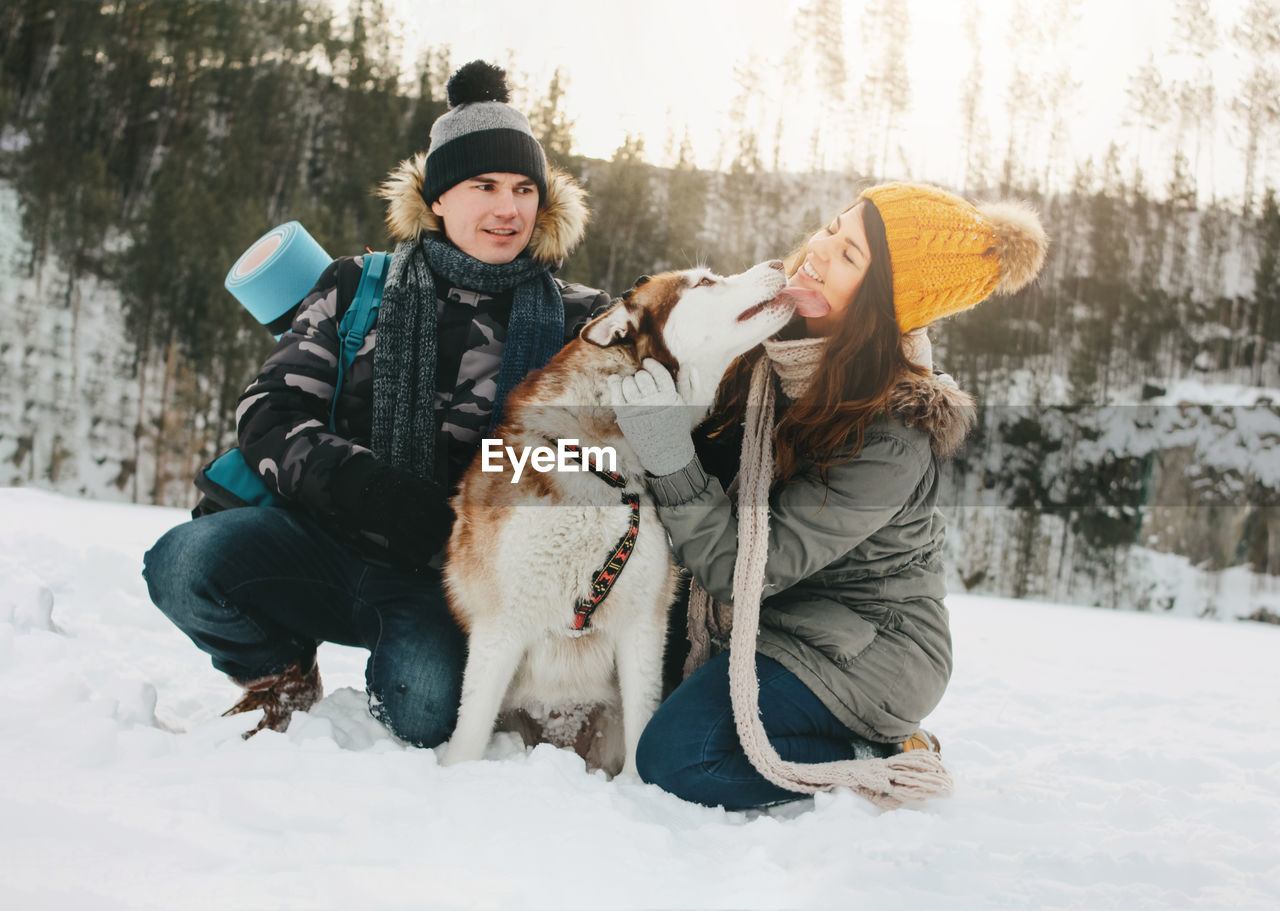 Happy couple with dog on snow covered field