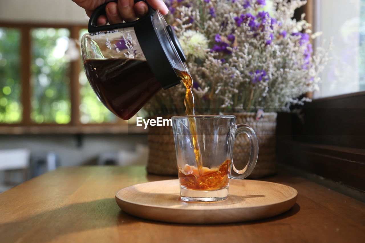 Midsection of person pouring drink in glass