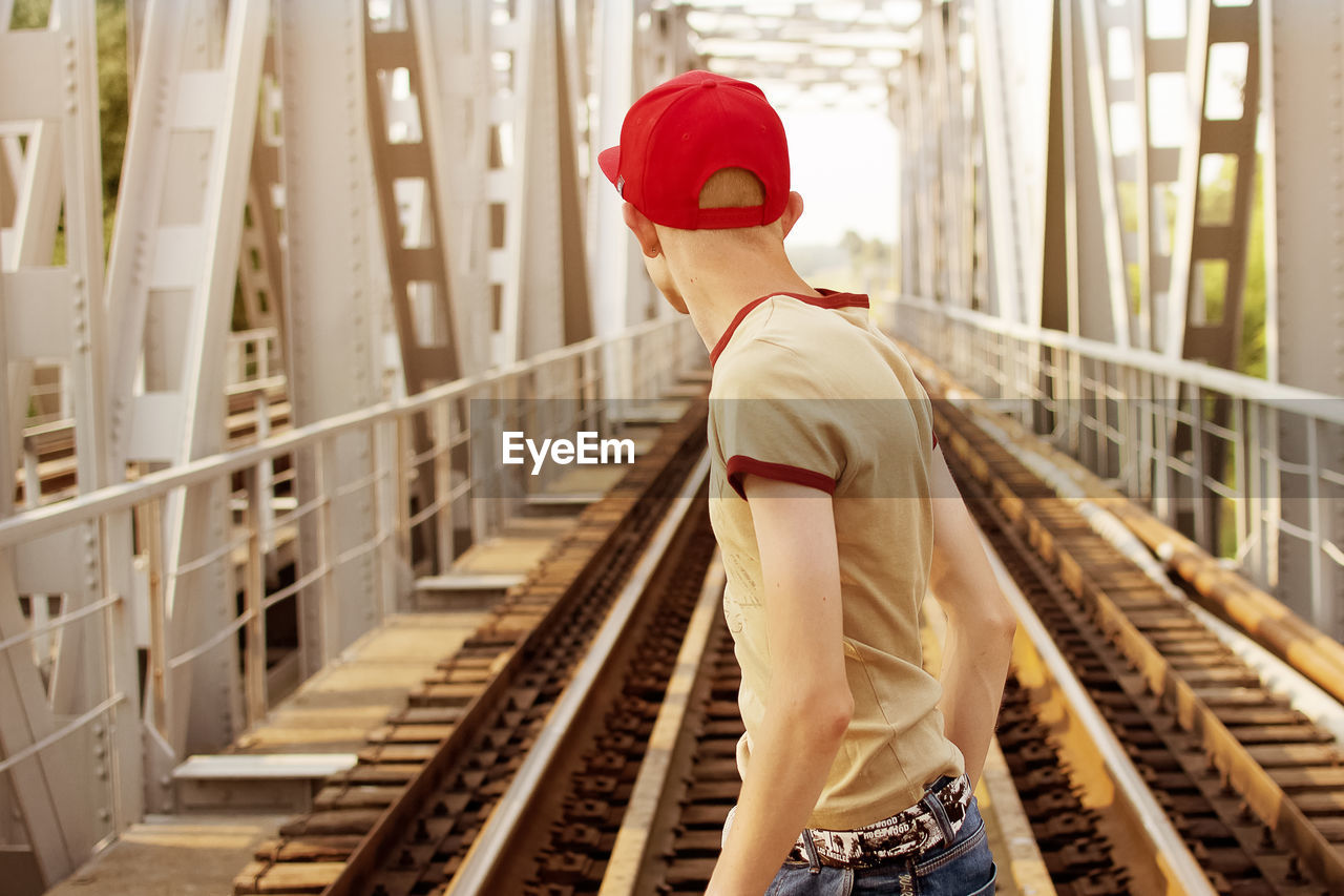 Rear view of teenage boy standing at railway bridge