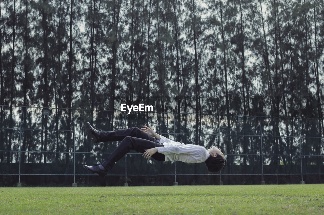 Full length of young man floating above turf