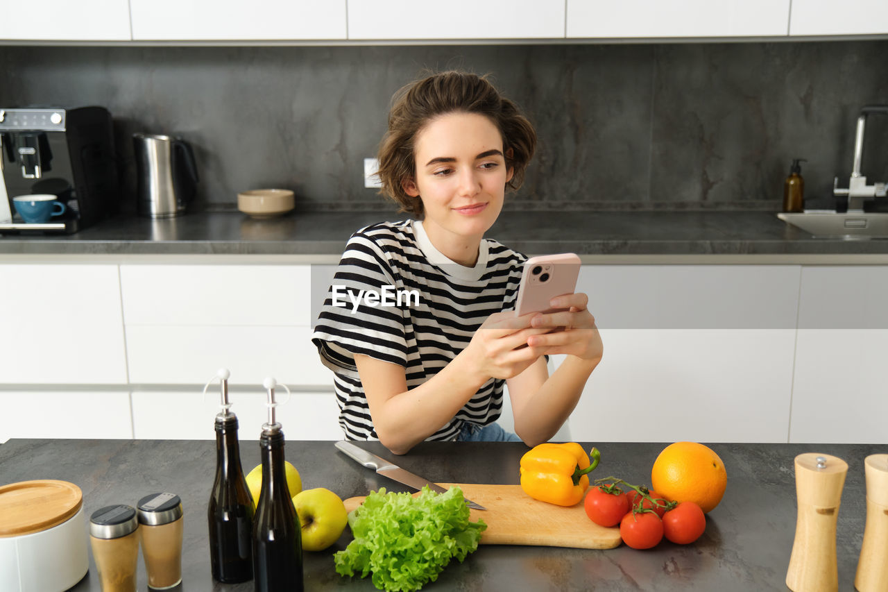 portrait of young woman using mobile phone while sitting at home