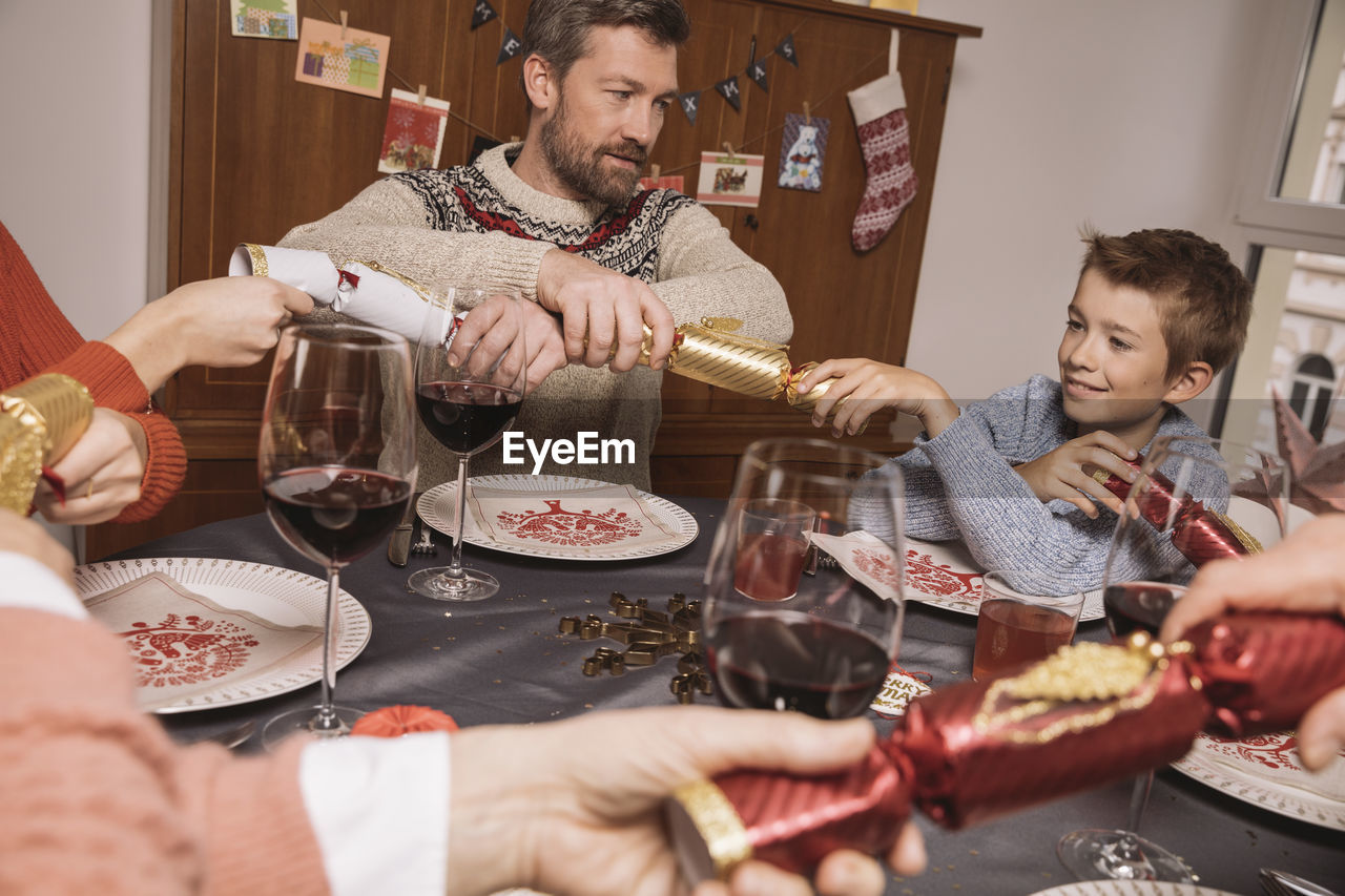 Pulling ends of christmas crackers at family table