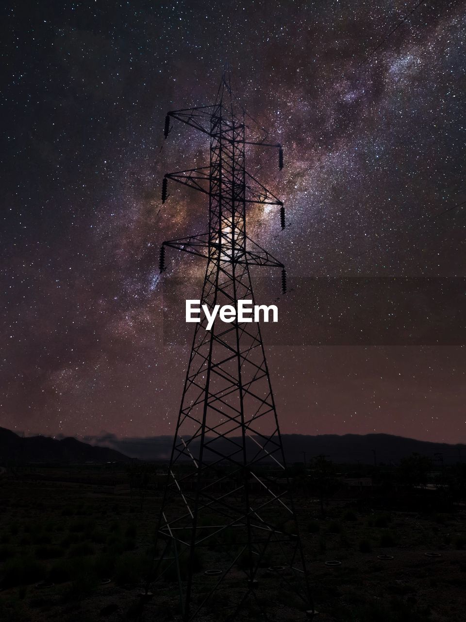 Low angle view of electricity pylon against sky at night