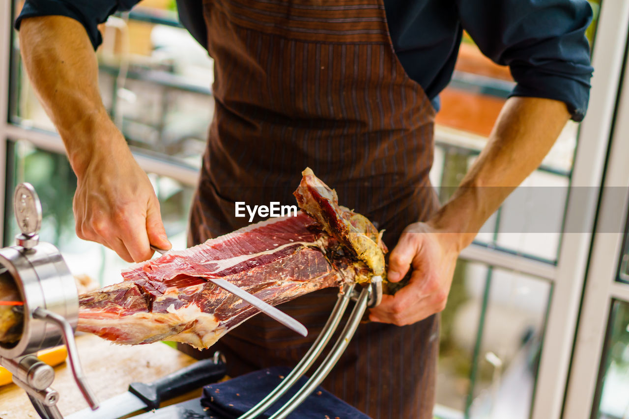 Midsection of man cutting meat