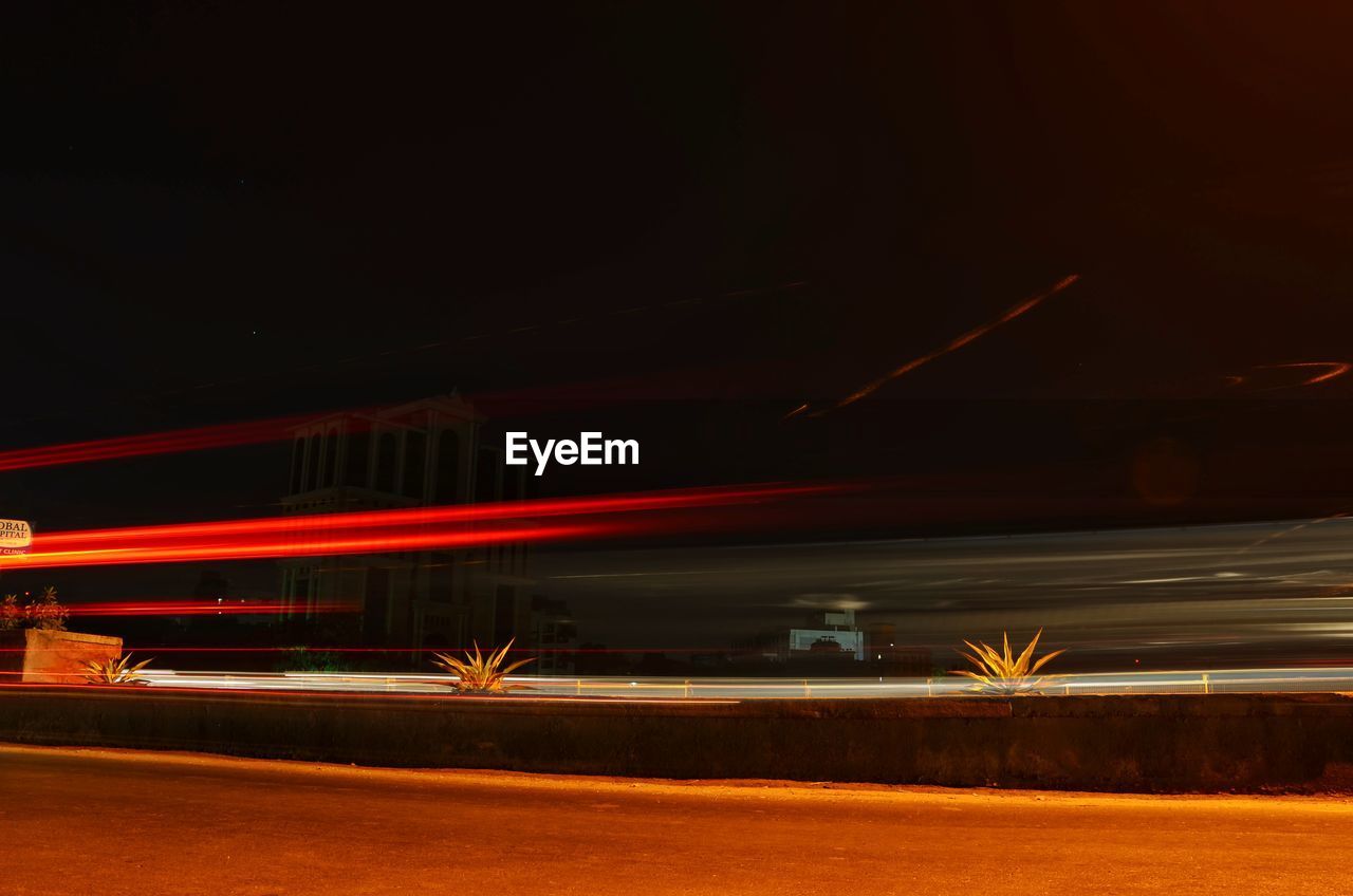 LIGHT TRAILS ON ROAD AGAINST SKY AT NIGHT