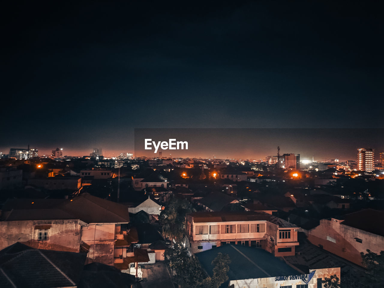 HIGH ANGLE VIEW OF ILLUMINATED BUILDINGS IN CITY AGAINST SKY