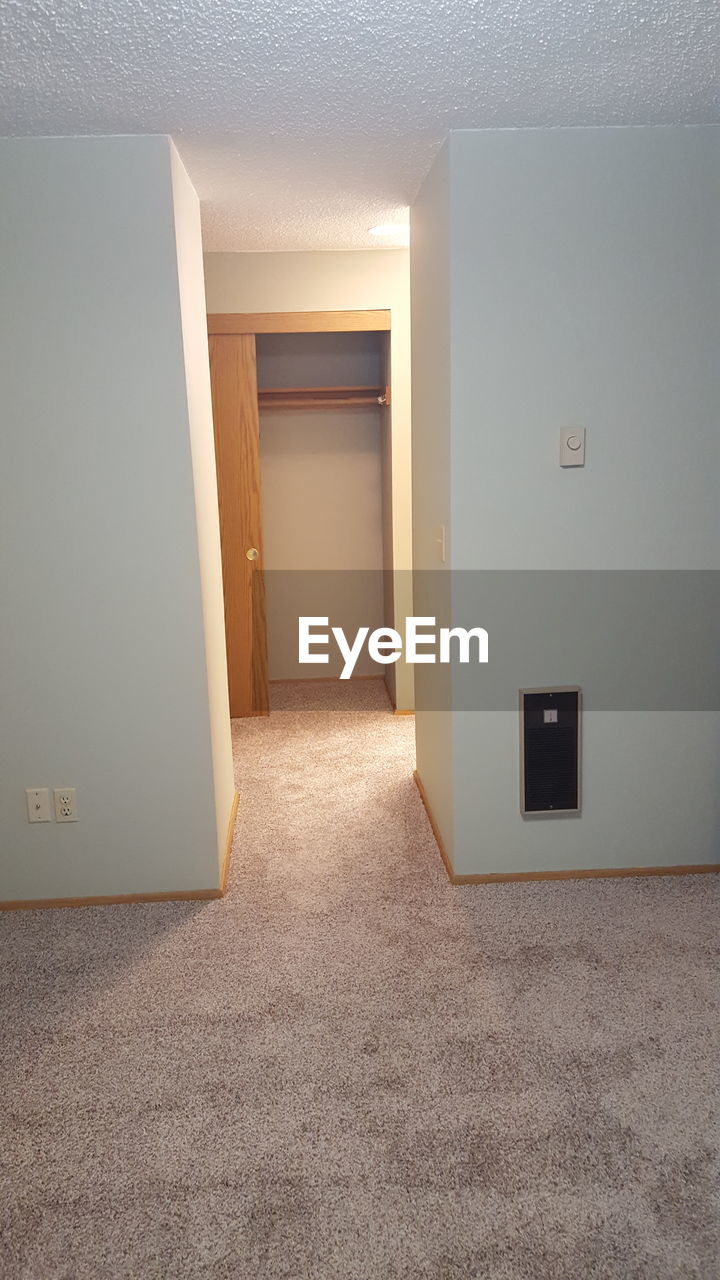 EMPTY CORRIDOR OF BUILDING WITH CLOSED DOOR