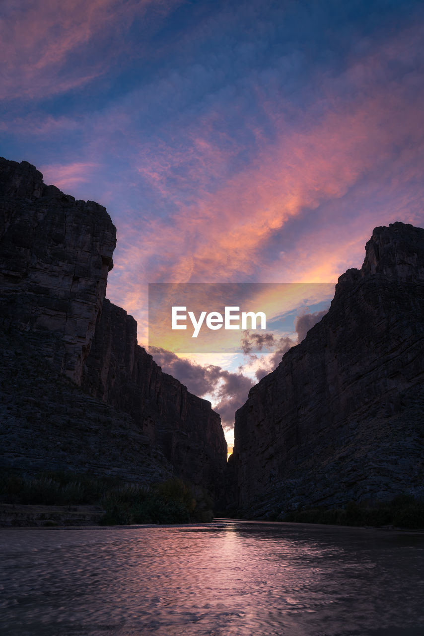 Scenic view of sea and mountains against sky during sunset