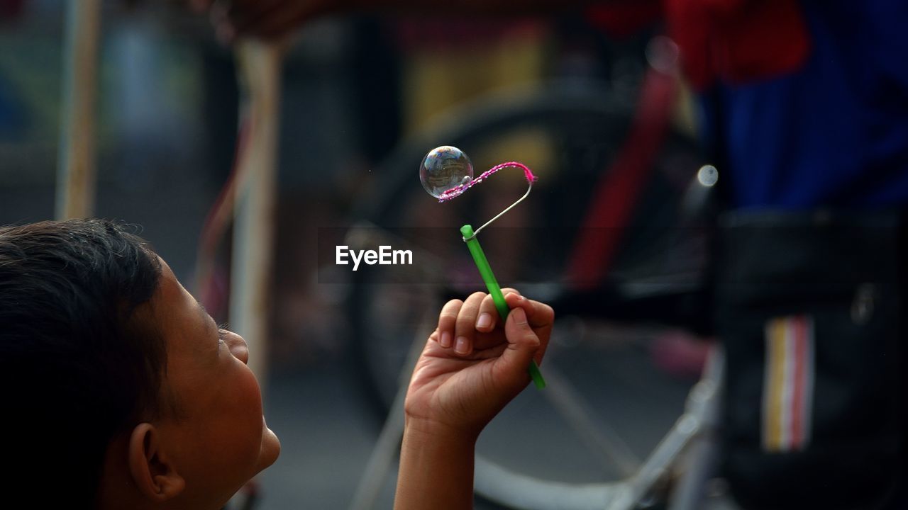 Close-up of little boy playing with bubble wand