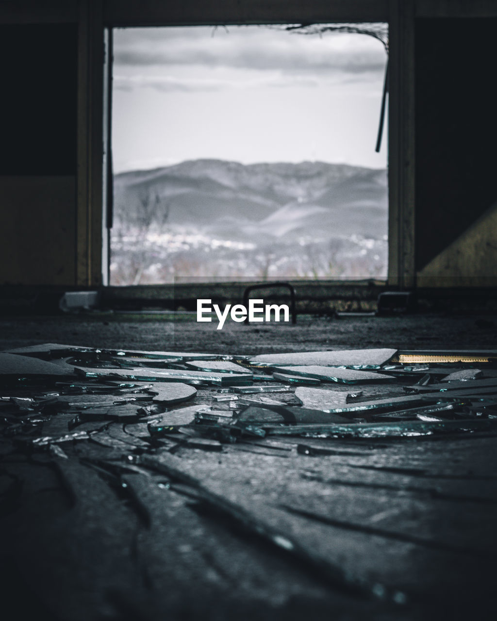 Close-up of broken glass window with mountain in the background