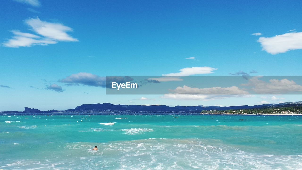 View of person swimming in sea against cloudy sky