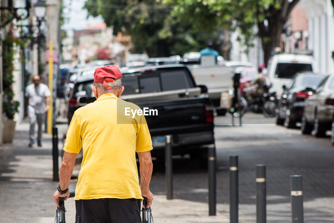 REAR VIEW OF MAN ON STREET AGAINST CITY