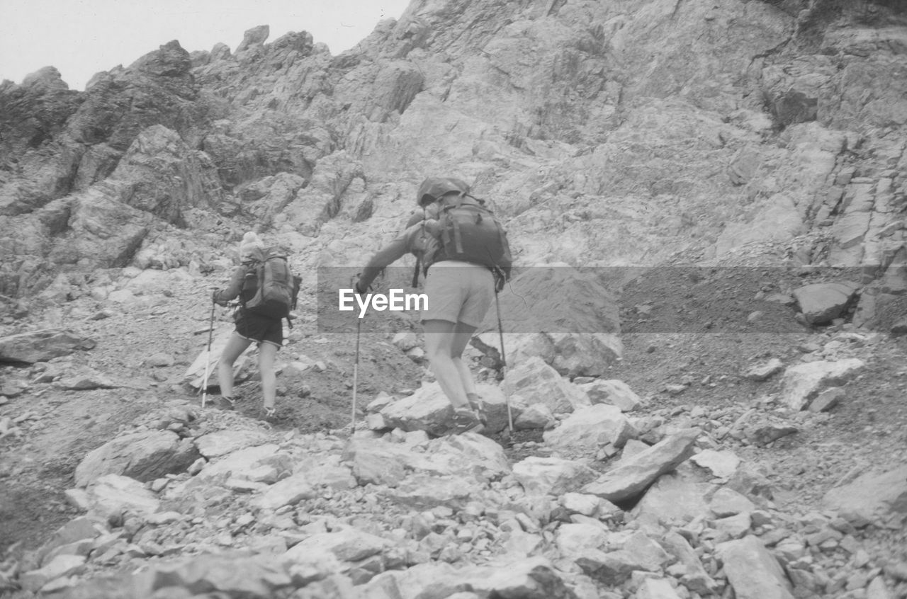 Rear view of backpackers climbing mountain