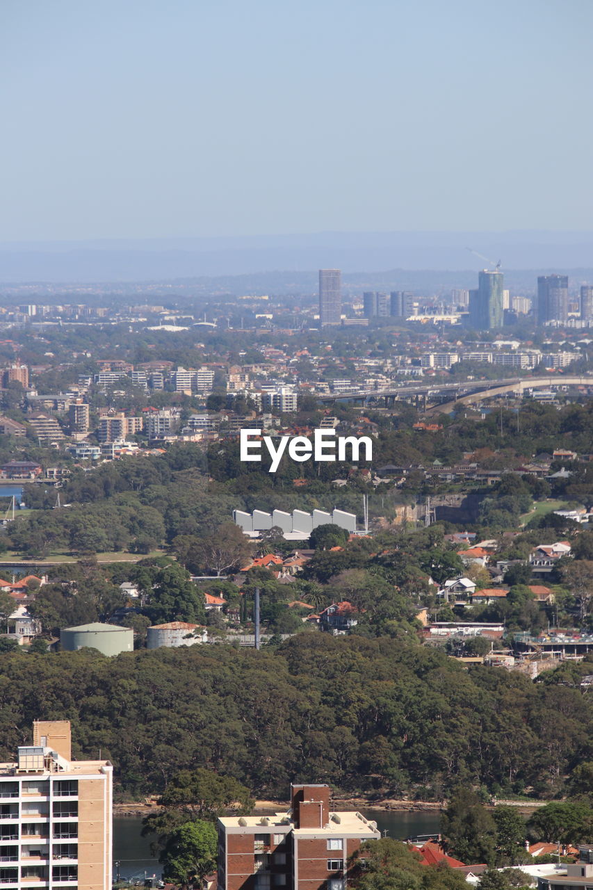 HIGH ANGLE VIEW OF TOWNSCAPE AND TREES AGAINST SKY