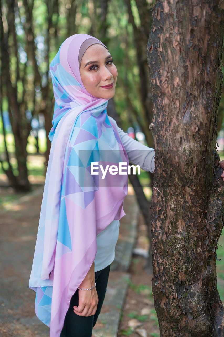 Portrait of smiling woman in hijab standing at park