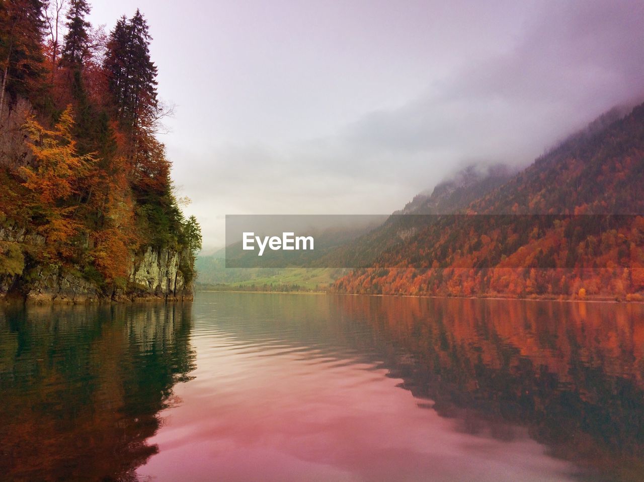 Scenic view of river amidst trees on mountains against sky