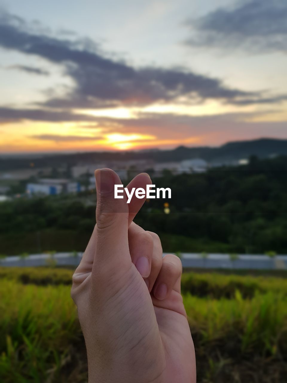 Cropped hand against sky during sunset