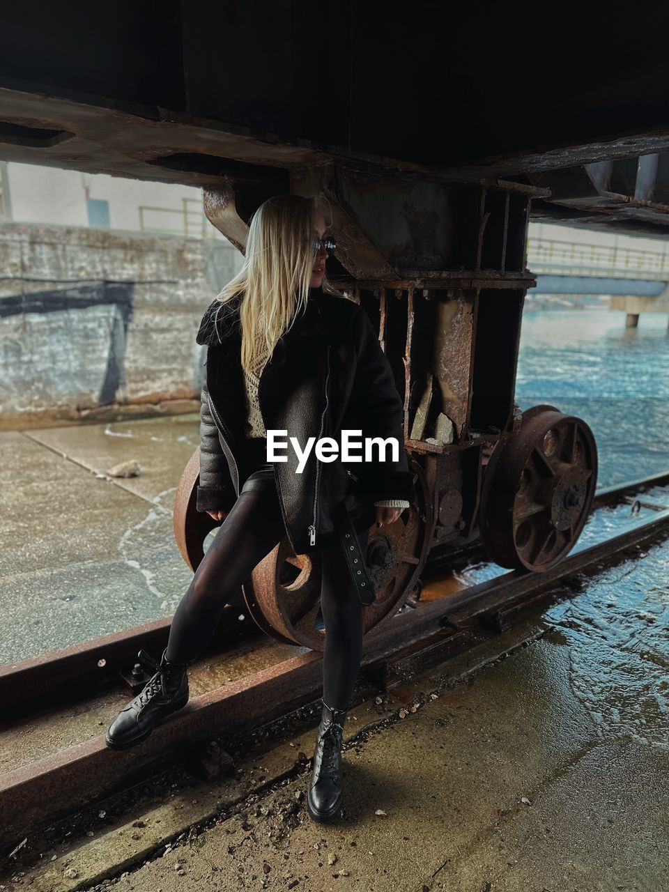 Rear view of young woman sitting on bridge