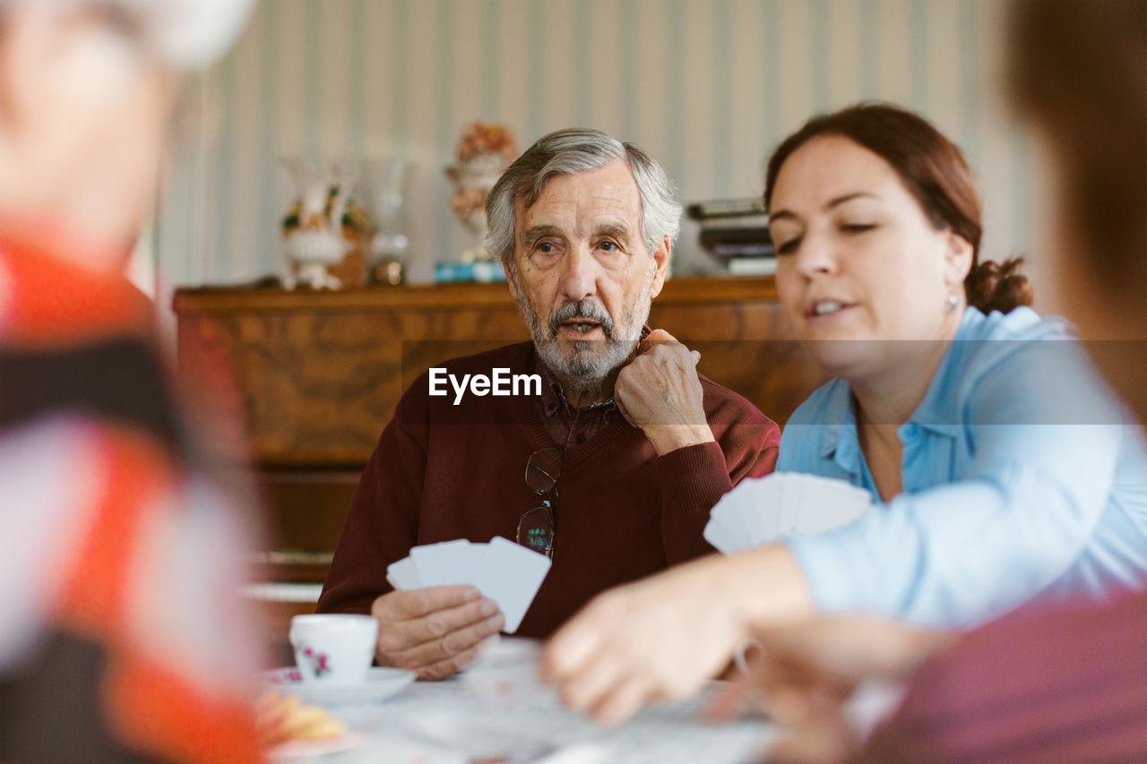 Senior man playing cards with family at home