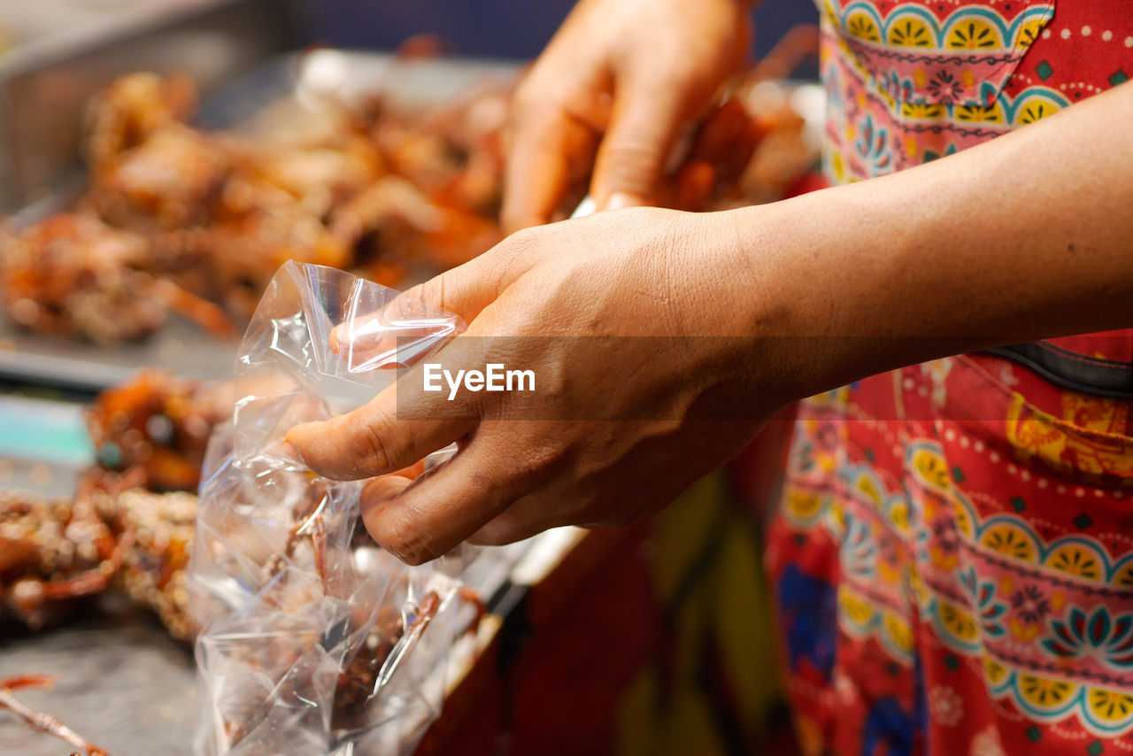 hand, food, food and drink, adult, market, retail, celebration, women, tradition, business, dish, close-up, holding, baked, business finance and industry, focus on foreground, market stall, freshness, event, vendor, midsection, selective focus, one person, meal, selling
