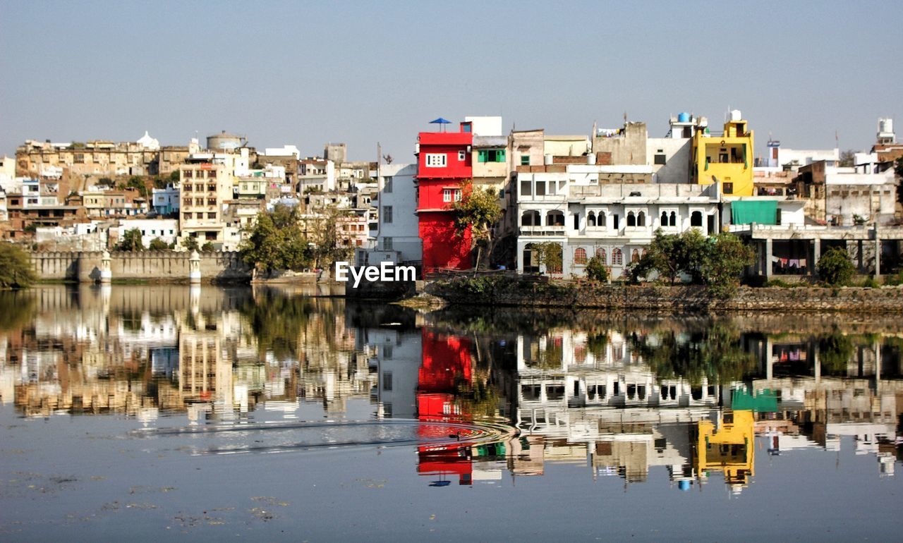 Reflection of buildings in lake against clear sky