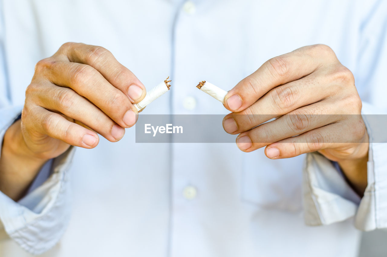 Midsection of man breaking cigarette 