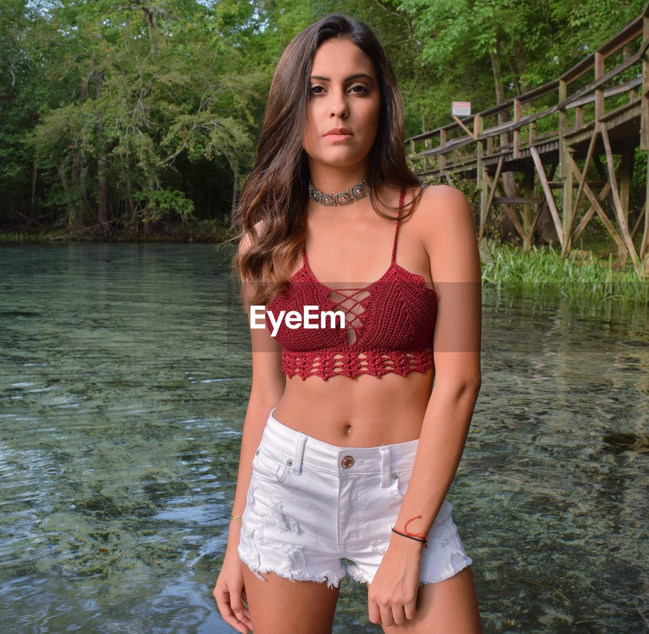 Portrait of beautiful young woman standing against lake