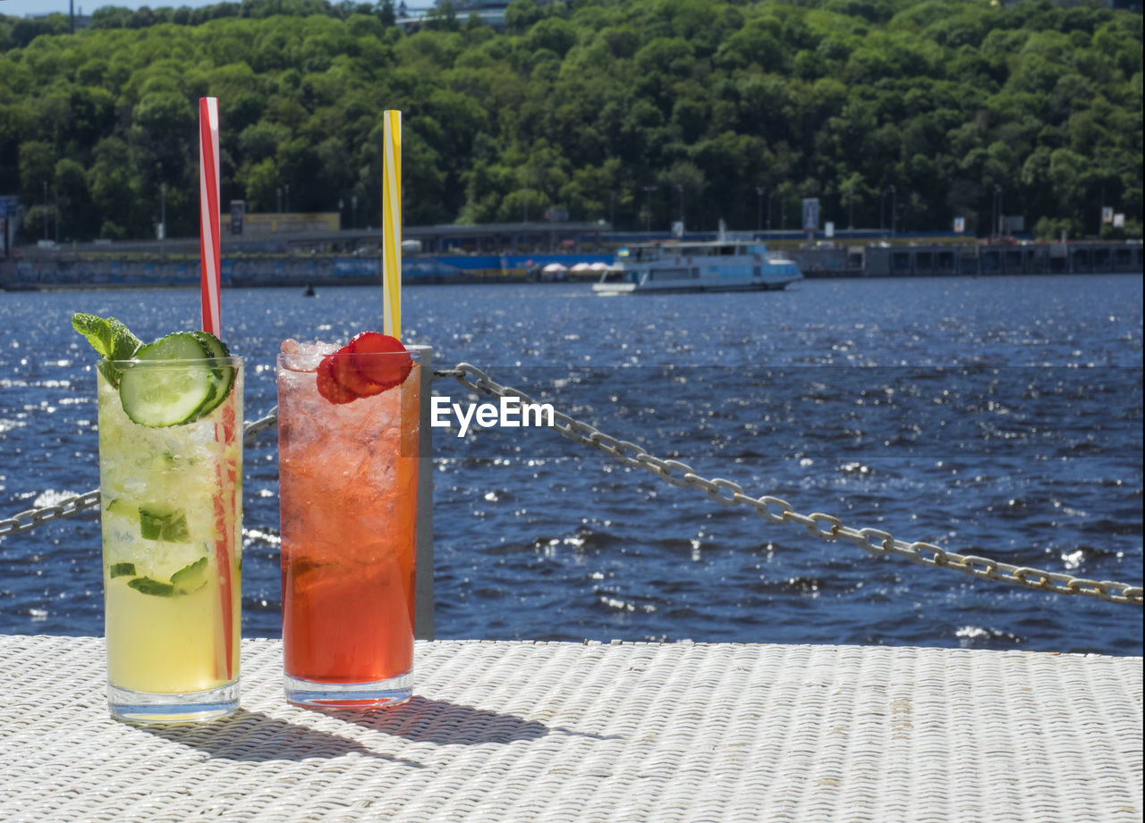 Close-up of lemonades in glasses on pier against sea