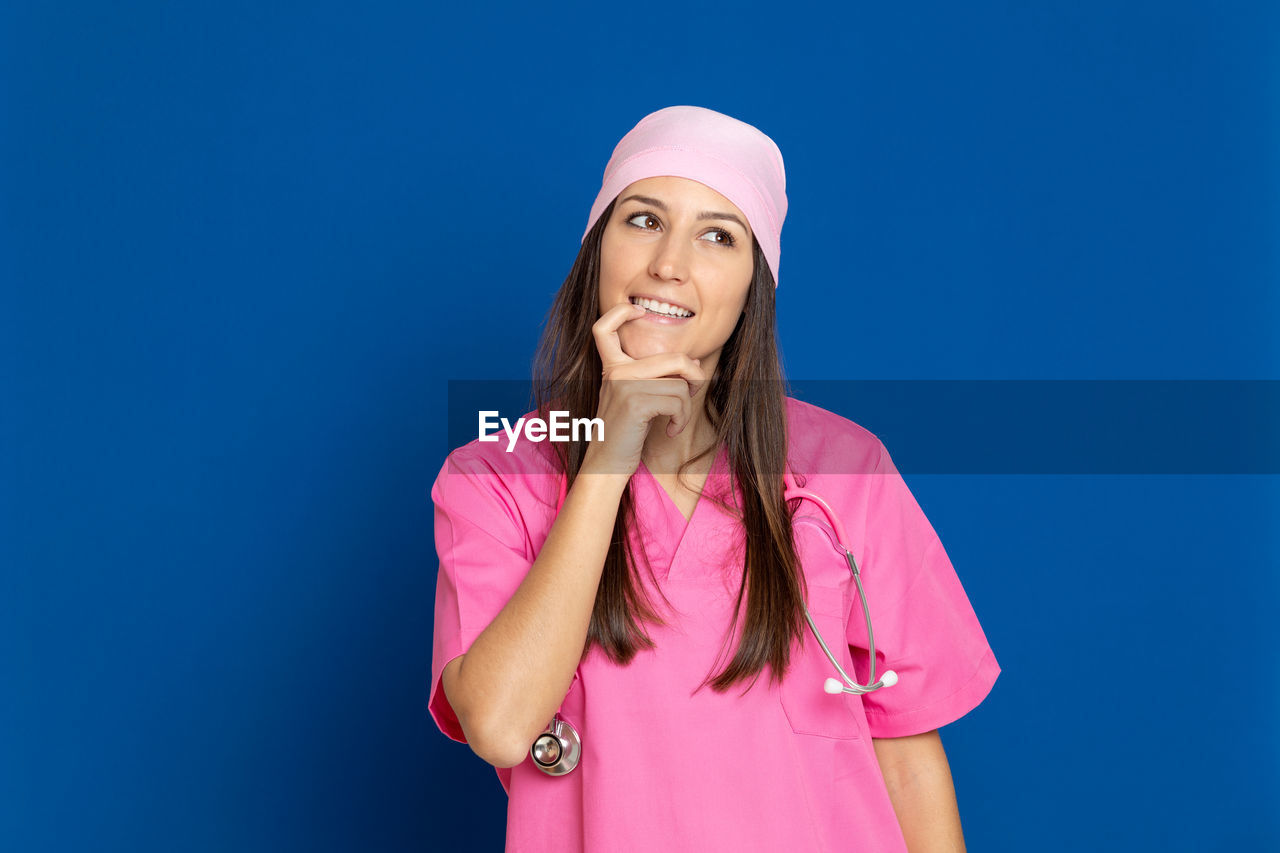 PORTRAIT OF BEAUTIFUL YOUNG WOMAN STANDING AGAINST PINK BLUE SKY