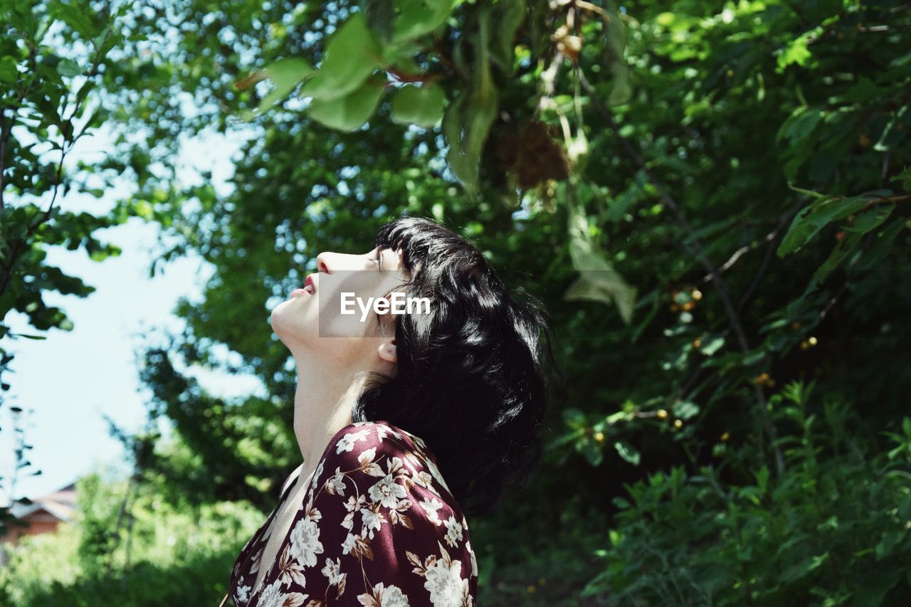 Side view of woman standing against trees