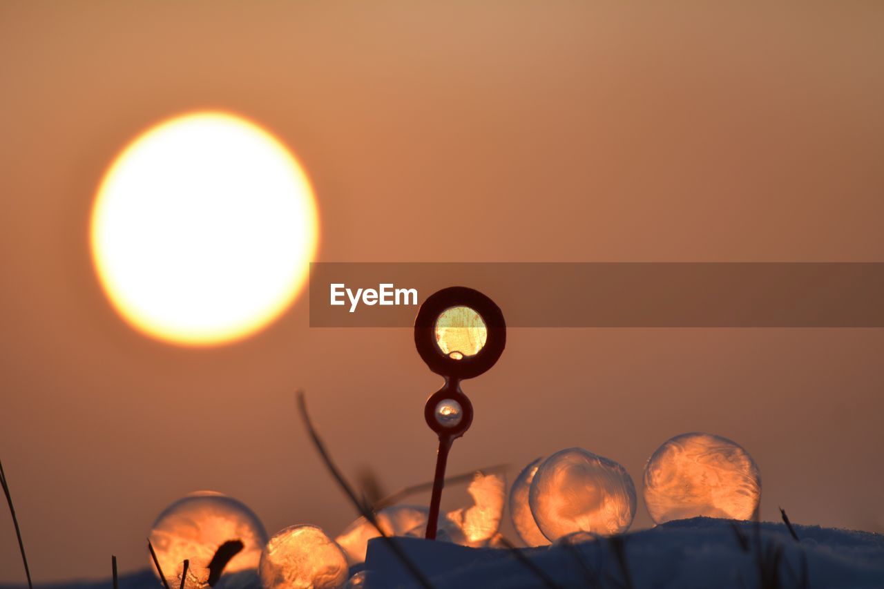 Low angle view of illuminated lamp against sky during sunset