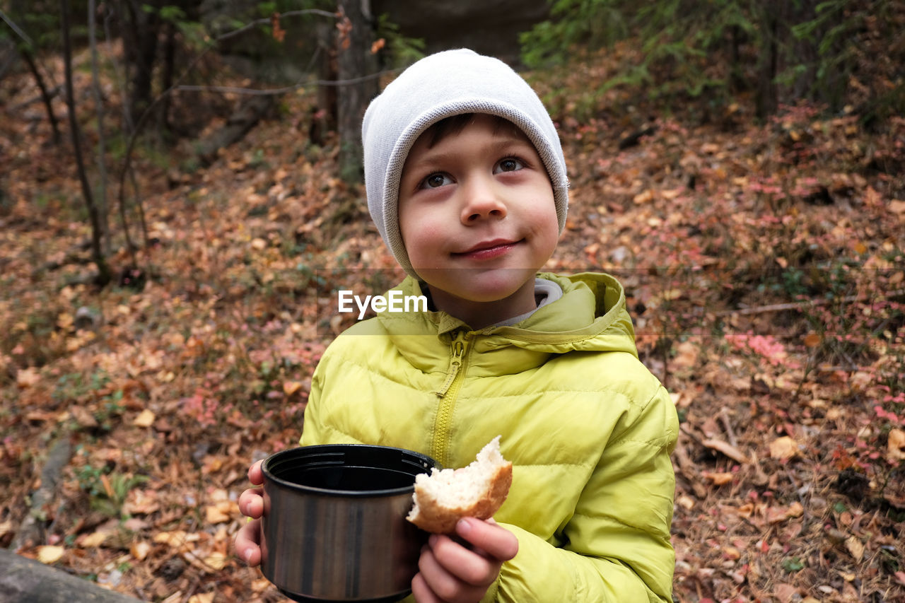 Boy with hot drink in forest