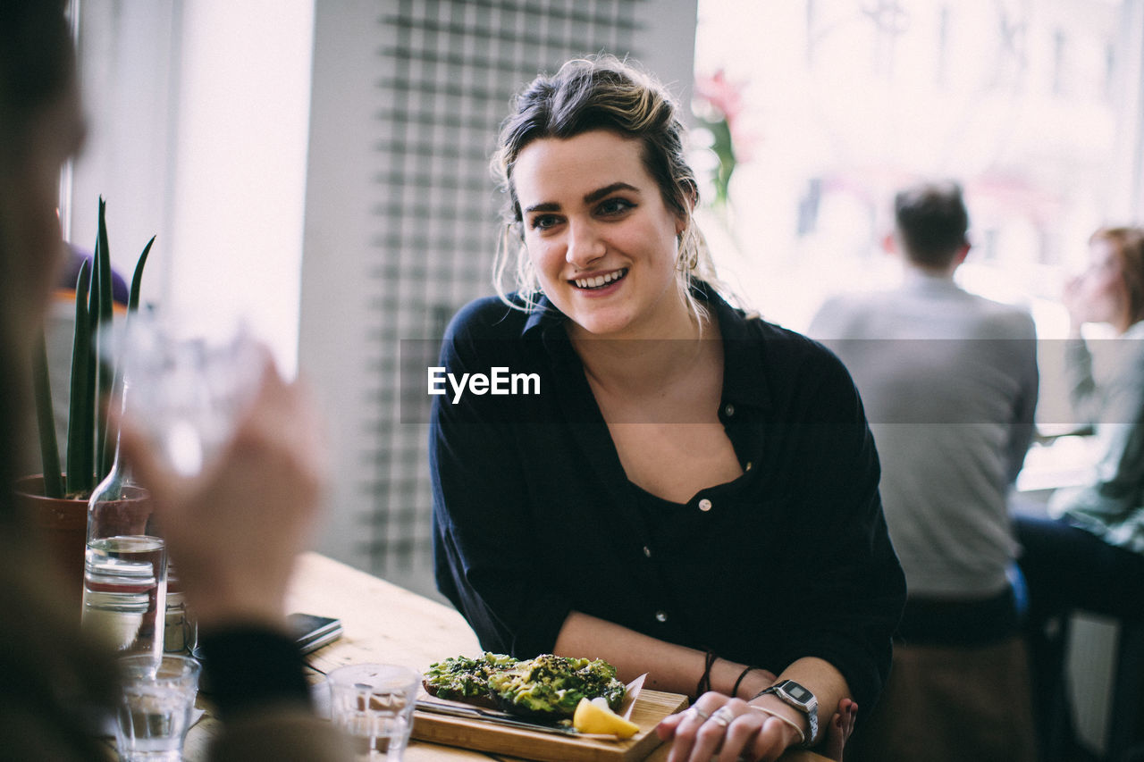 Smiling young woman sitting on table at restaurant