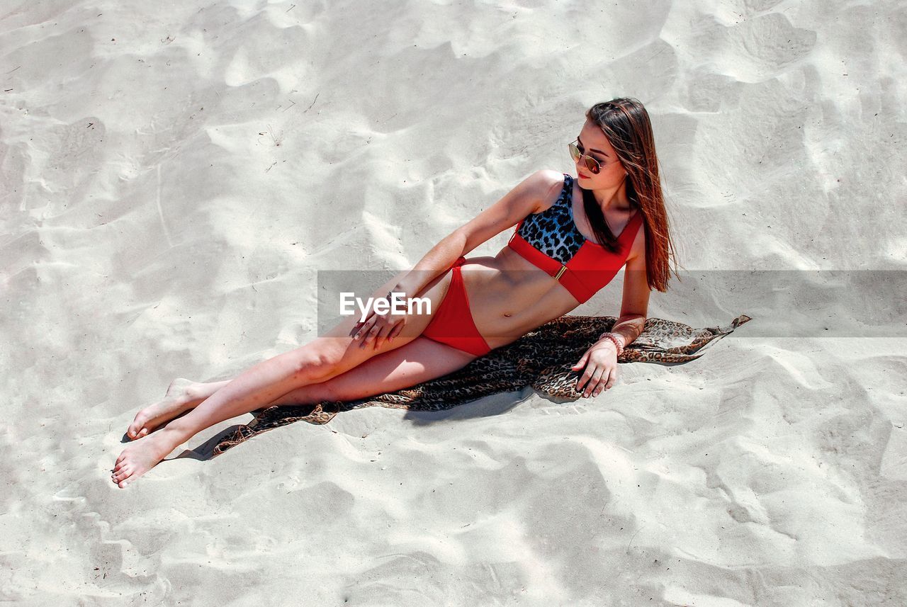 High angle view of woman in bikini lying at beach