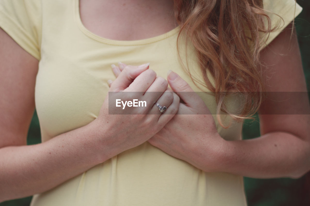 Midsection of woman standing with hands clasped