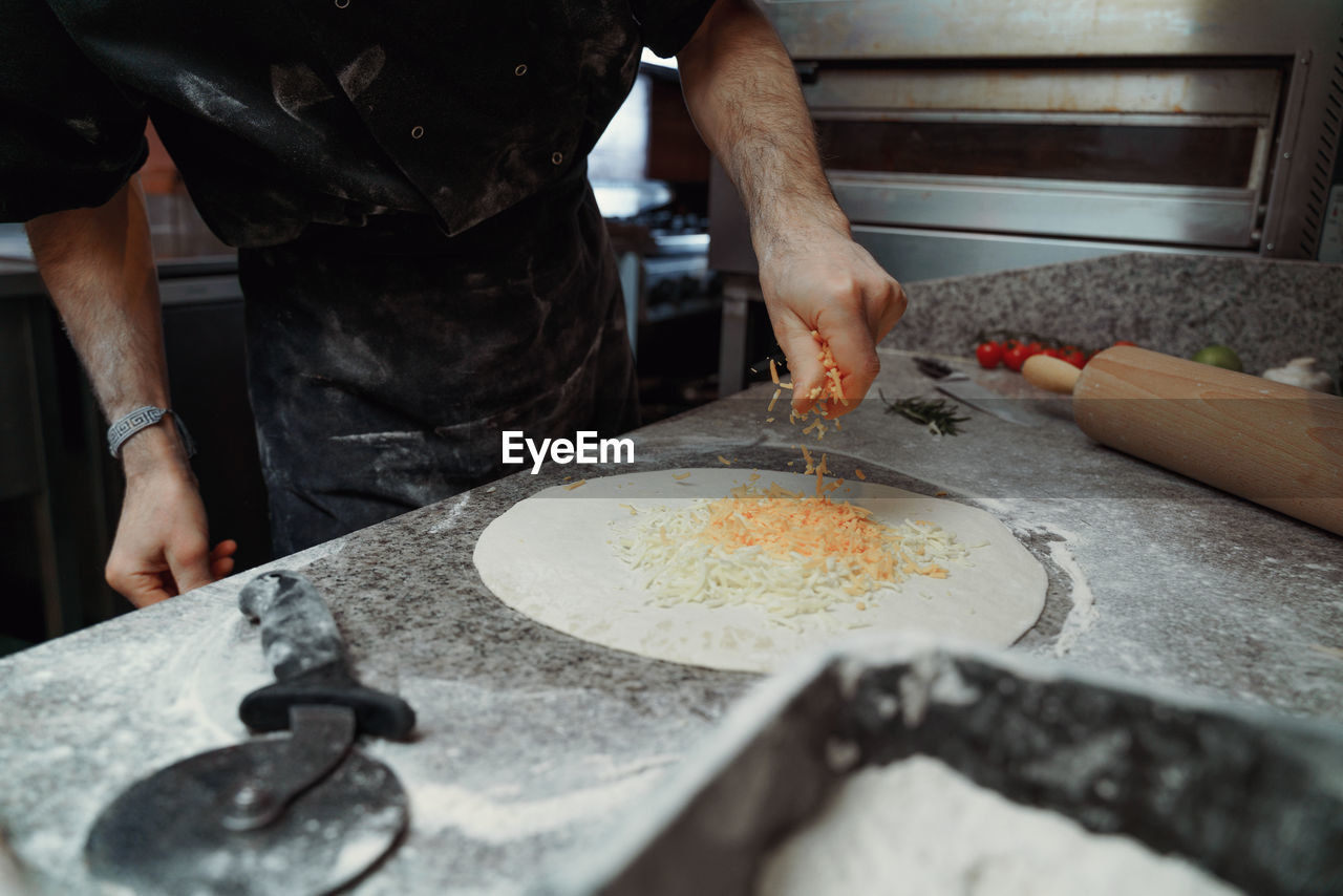 Midsection of man preparing pizza