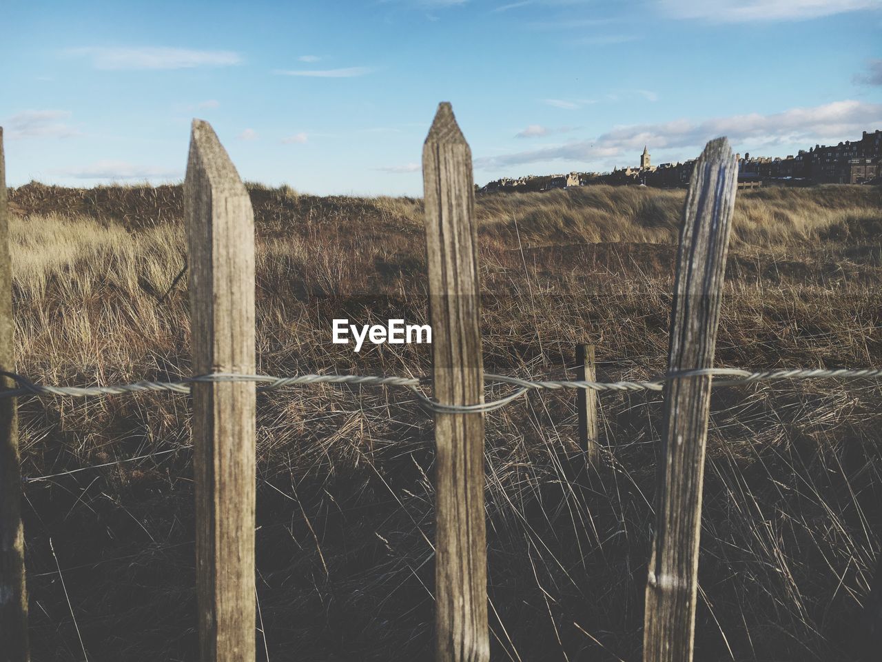 Wooden fence on field against sky