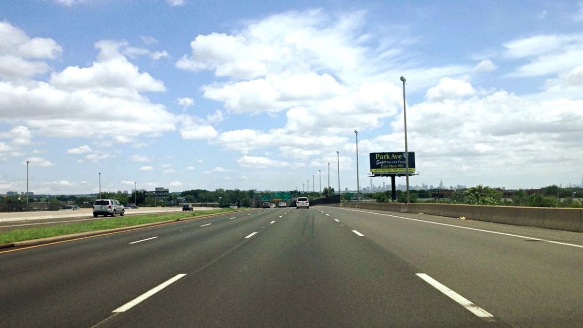 ROAD PASSING THROUGH HIGHWAY AGAINST CLOUDY SKY