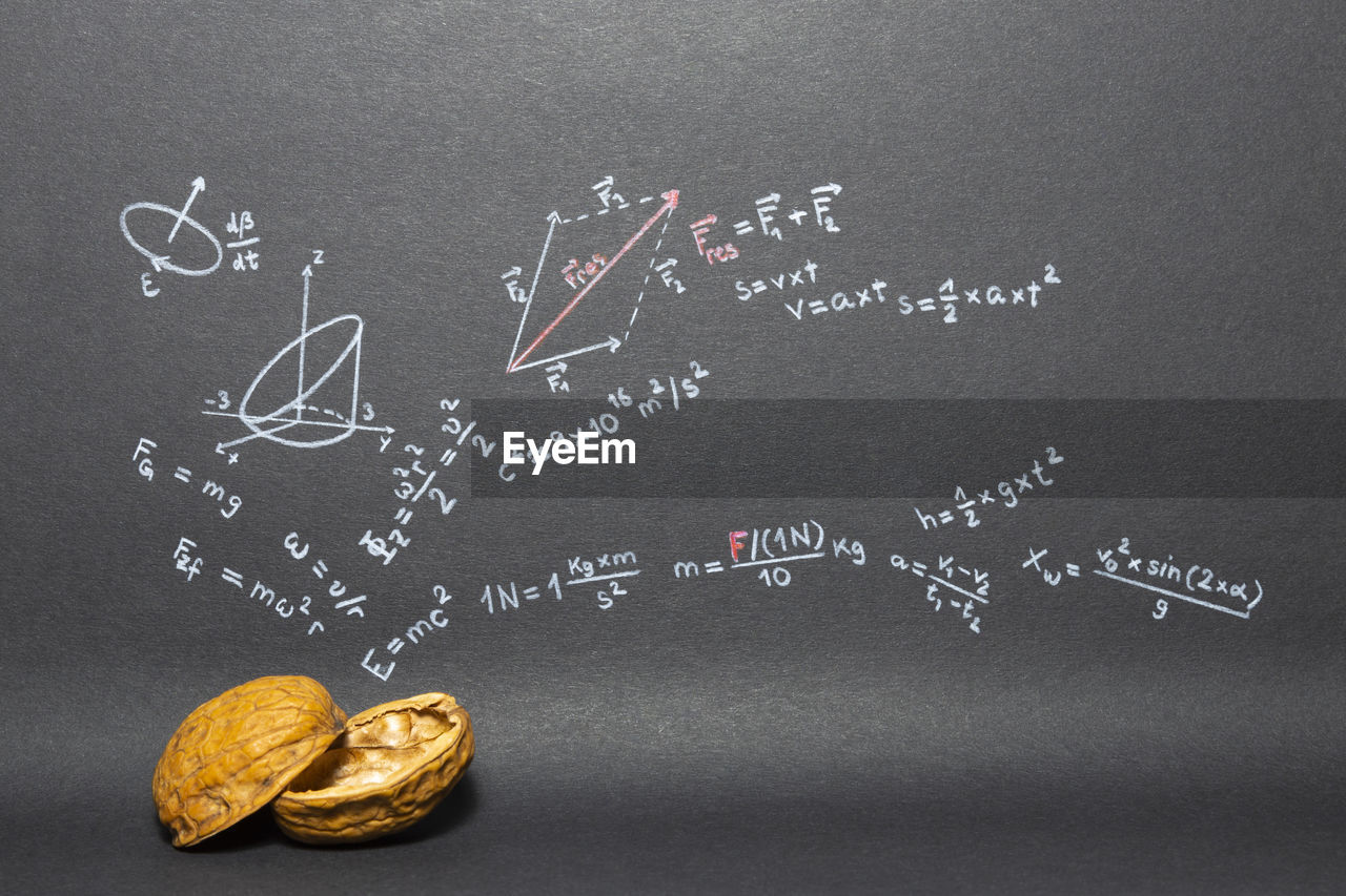 Close-up of walnut against formulas on blackboard