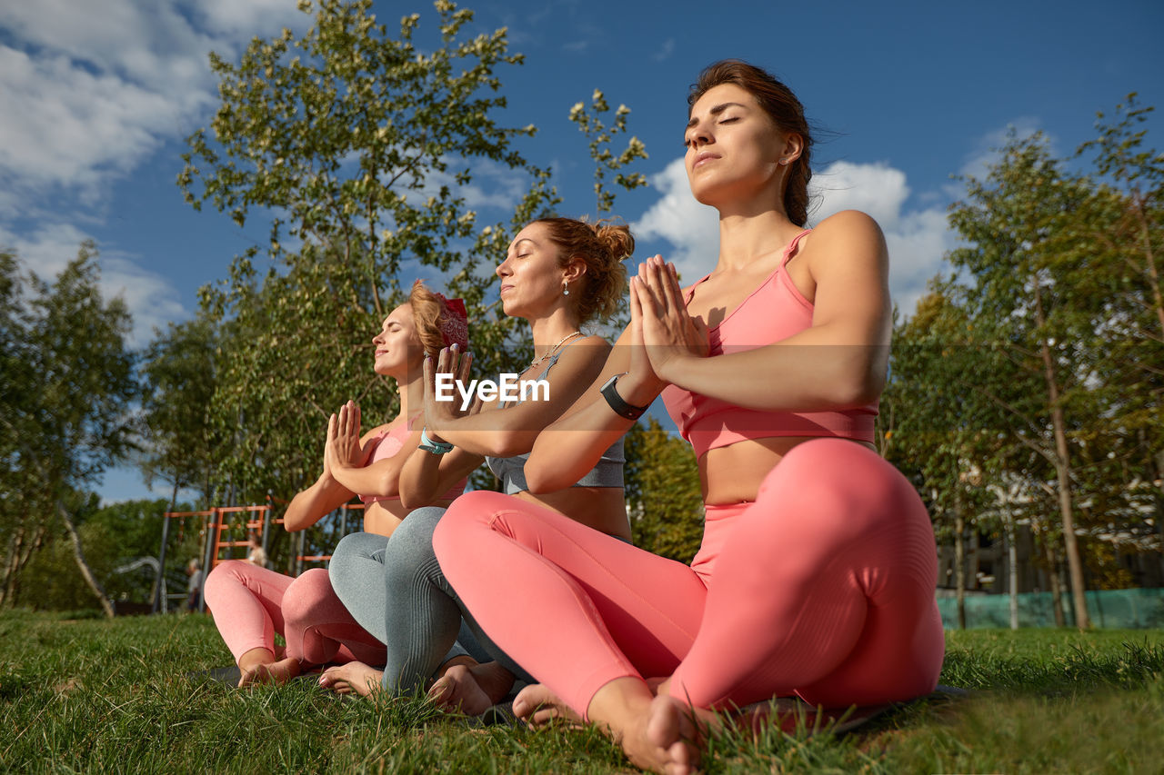 friends sitting on grassy field against sky