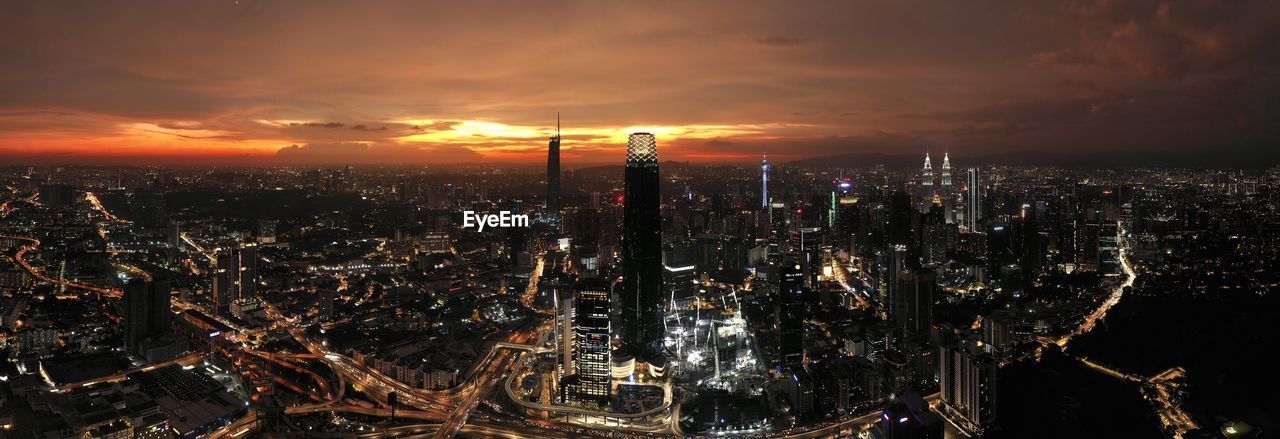 Illuminated cityscape against sky during sunset