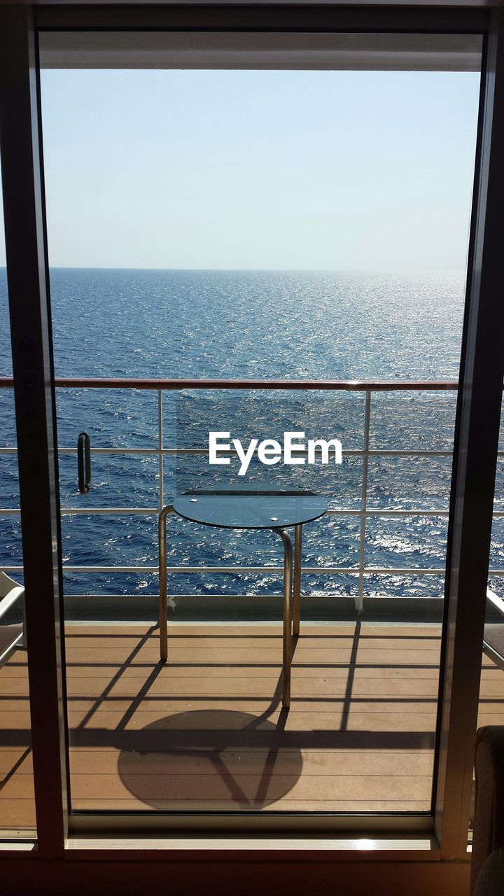 Scenic view of sea against clear sky seen from glass door in cruise ship