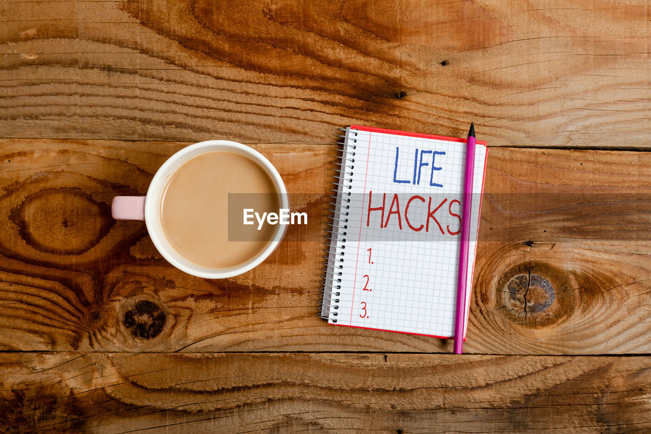 HIGH ANGLE VIEW OF COFFEE ON TABLE WITH OPEN BOOK